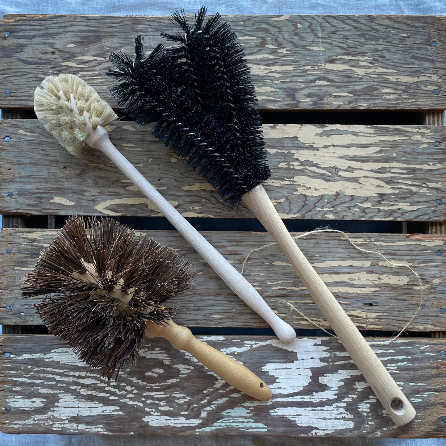 Redecker Lawnmower Brush for cleaning frame and blades of lawnmower pictured with Water Bottle brush and Flowerpot brush on wooden background