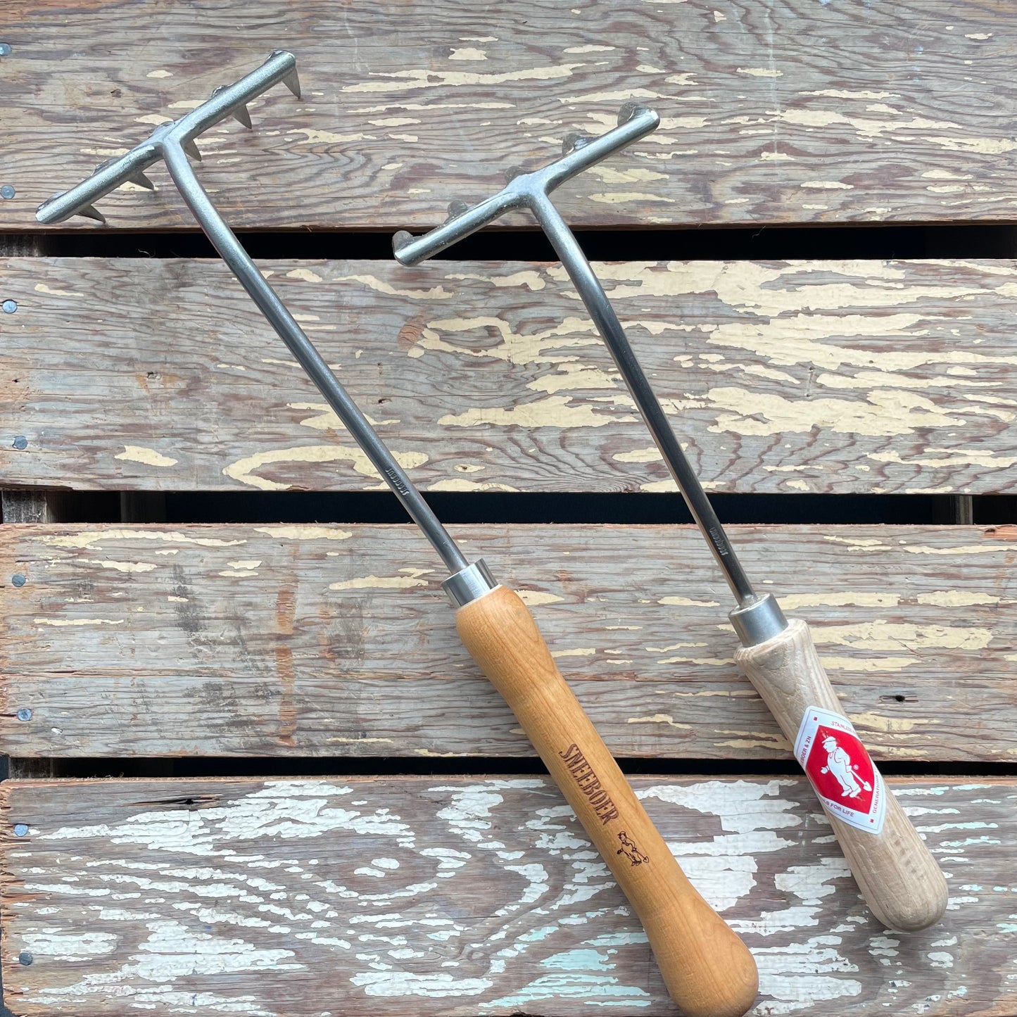 Two Sneeboer Hand Rakes displayed on wooden crate