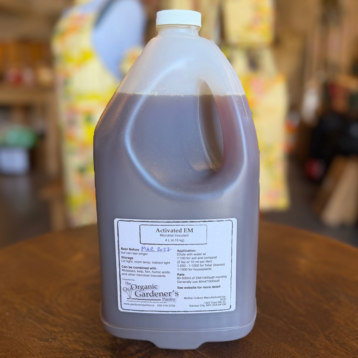 A 4 litre plastic jug of Organic Gardener's Activated EM liquid fertilizer on a wooden table