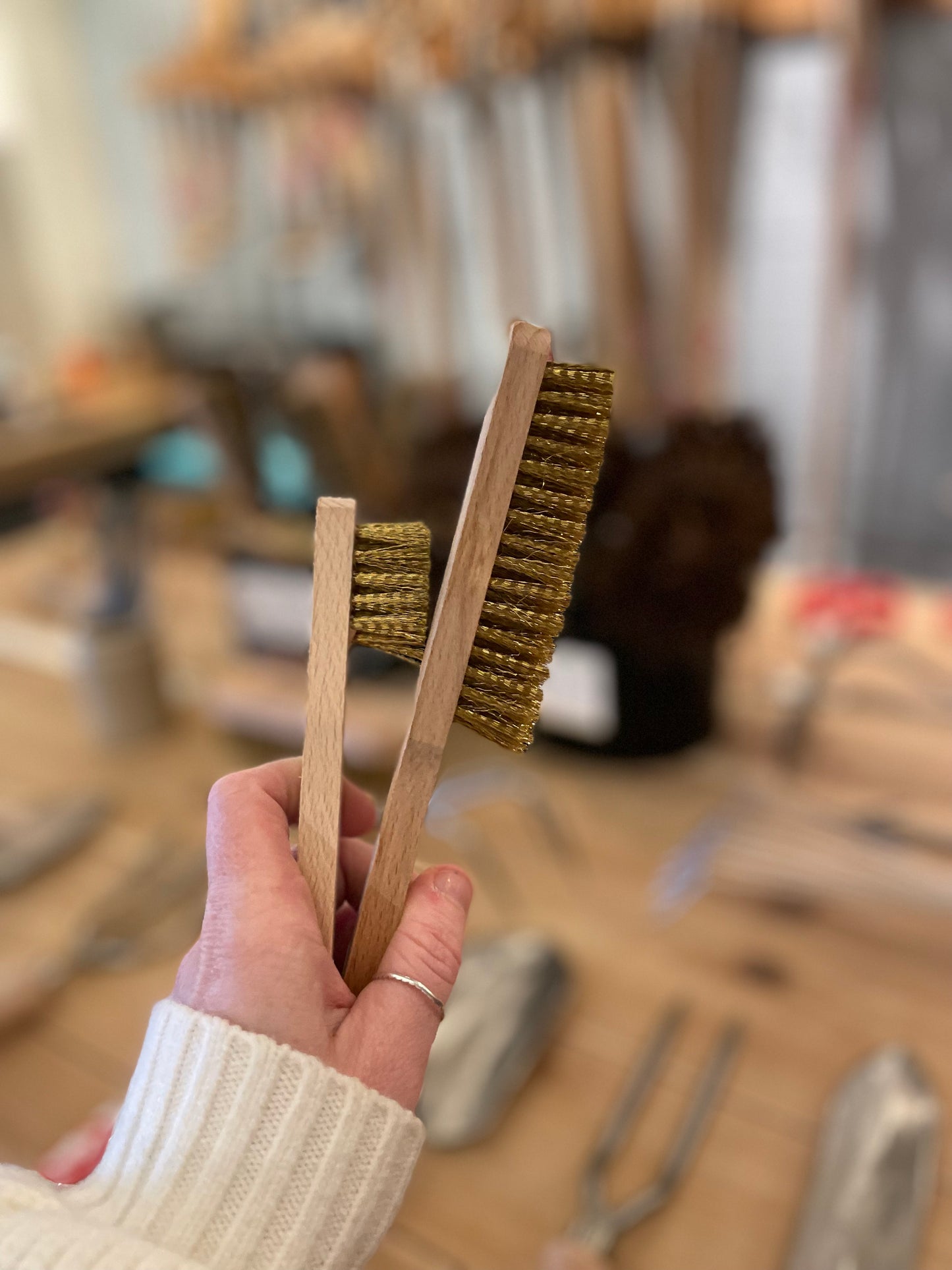 Size comparison of two Redecker Brass Wire Brushes being held in a persons hand