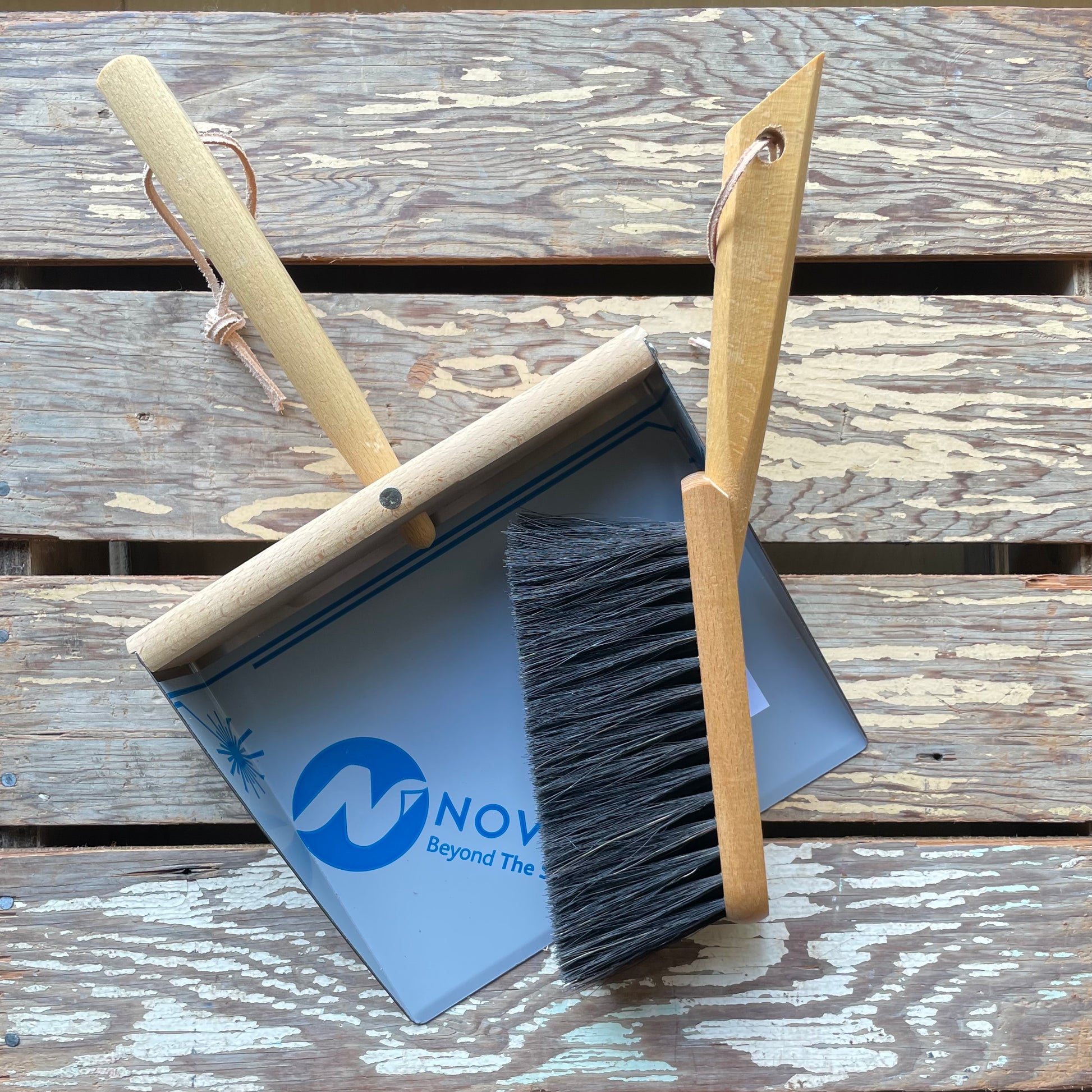 Overhead shot of Redecker Hand Brush & Dustpan set for cleaning and sweeping pictured on wooden crate