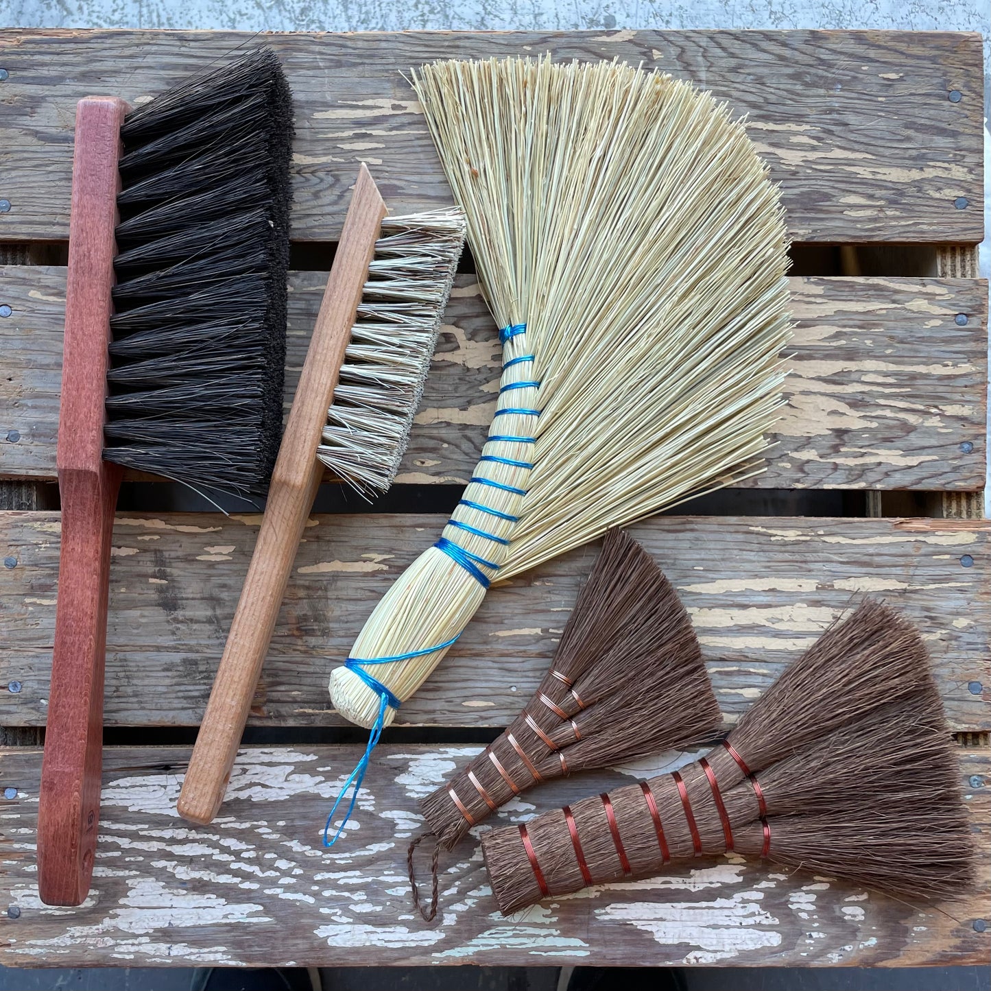 Redecker hand brooms and brushes consisting of rice straw and other plant fibres on a wooden background